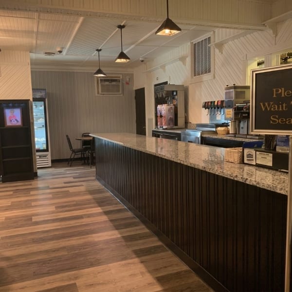 Restaurant interior featuring a long granite counter, drink dispensers, and light wood-look flooring.