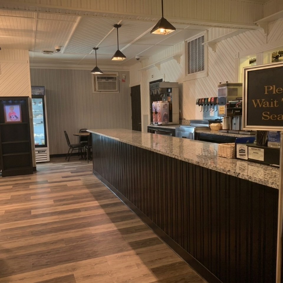 Restaurant interior featuring a long granite counter, drink dispensers, and light wood-look flooring.
